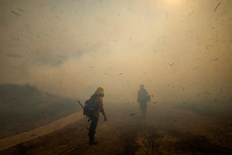 Firefighters face strong winds as they head up a hillside to battle a wind driven wildfire near Irvine, California