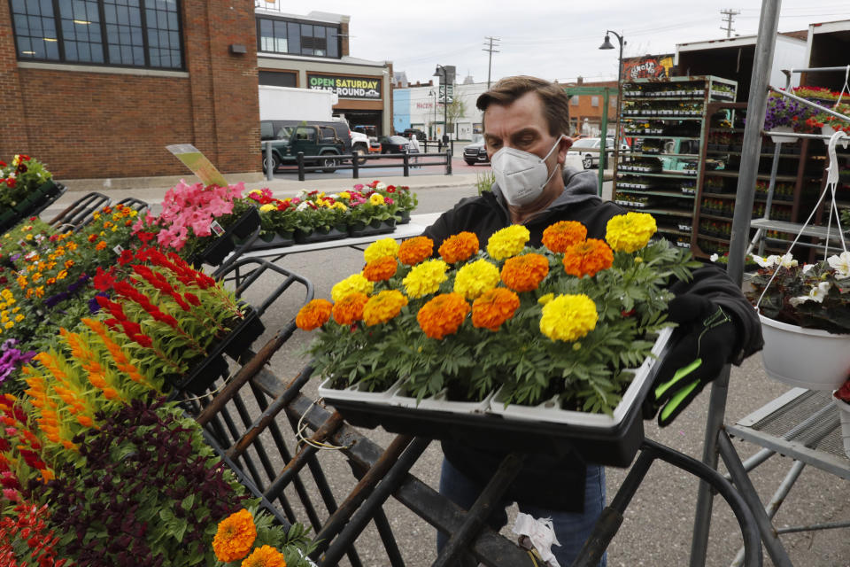 John Spens of Geier Farms sets up at the Detroit Farmers Market, Saturday, May 2, 2020, in Detroit. Farmers, growers and operators of open-air markets are heading into one of their busiest times of year while facing the added challenge of the coronavirus. Shoppers venturing to farmers markets this spring are likely to see a lot fewer vendors and fellow customers. The ones they do see will be taking precautions such as the wearing of face masks and frequent use of hand sanitizer. (AP Photo/Carlos Osorio)