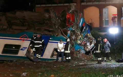 Firemen and rescue personnel work next to a regional train plowed into a big-rig truck that stopped on the tracks, in Caluso, outside Turin, Italy - Credit: AP