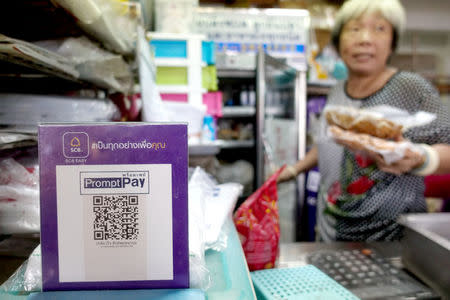 An advertisement board displaying a QR code is seen as a vendor works at a market in Bangkok, Thailand, November 22, 2017. REUTERS/Athit Perawongmetha