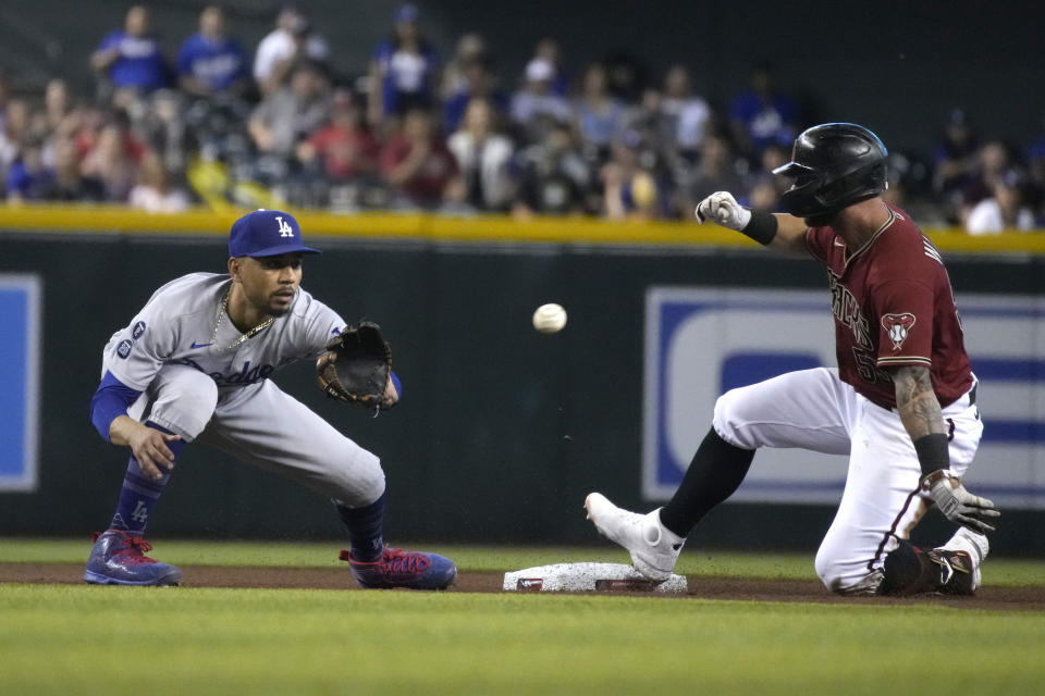 Arizona Diamondbacks' Christian Walker, right, advances to second base on a throwing error by Justin Turner with Mookie Betts, left, covering in the fourth inning during a baseball game, Sunday, Aug 1, 2021, in Phoenix. (AP Photo/Rick Scuteri)