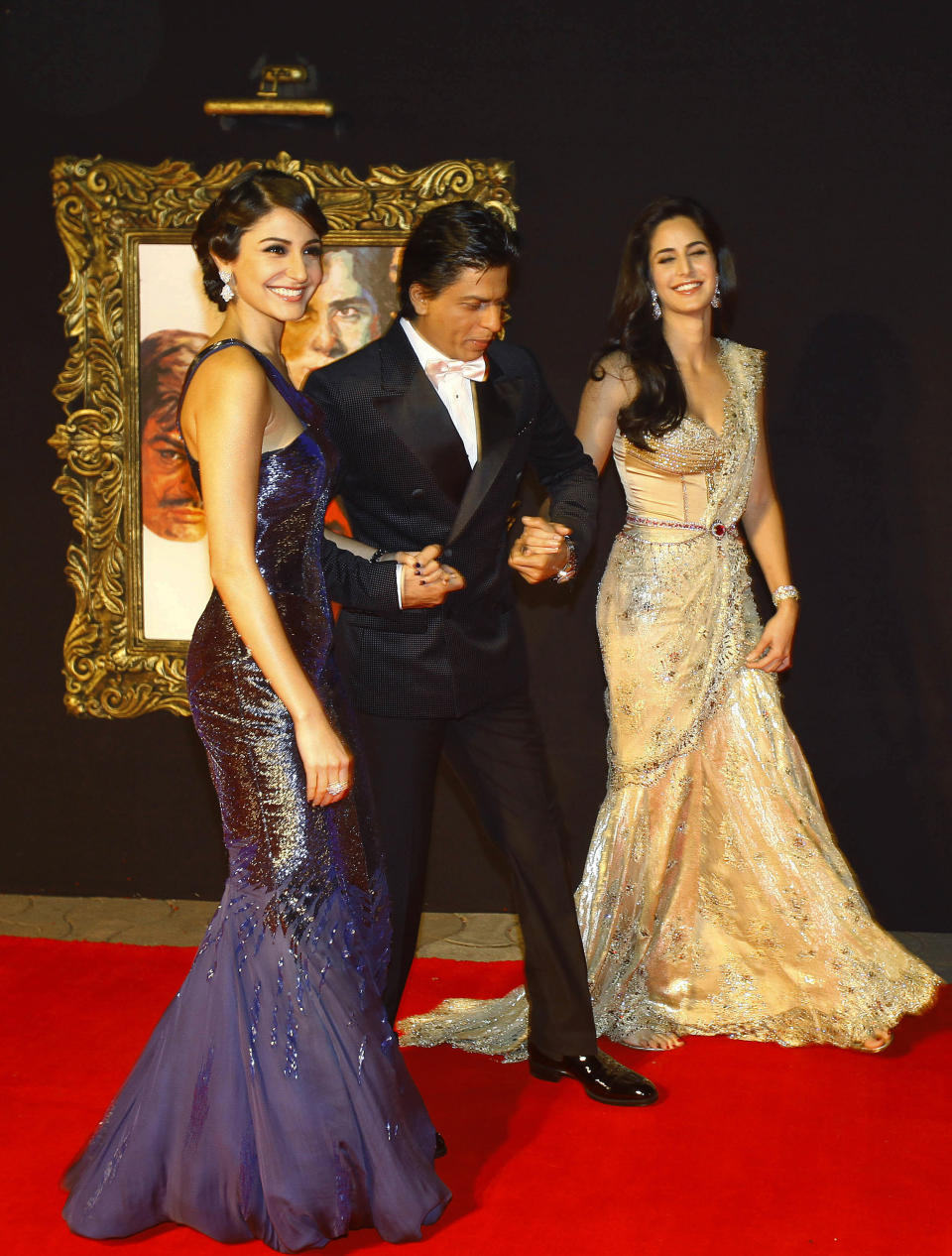 In this Monday, Nov. 12, 2012 photo, Bollywood stars Anushka Sharma, left, Shah Rukh Khan, center, and Katrina Kaif walk during the premier of their film "Jab Tak Hai Jaan" or "As long as I Am Alive" in Mumbai, India. Bollywood stars turned out in strength at the premiere of the movie for a final homage to movie mogul Yash Chopra, who died last month days after finishing the film. Chopra was known as the "King of Romance" for creating classic love stories that were immensely popular. (AP Photo/Rafiq Maqbool)