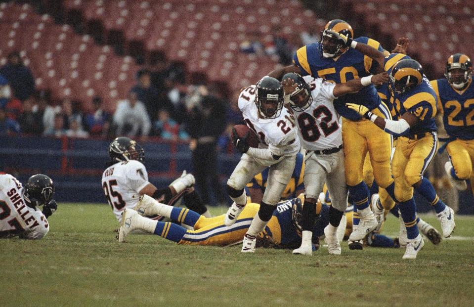 The Falcons' Deion Sanders carries the ball for a 10-yard gain as teammate Jason Philips tries to hold back two Rams