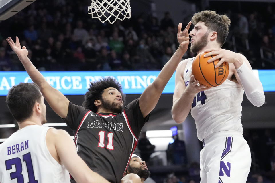 Northwestern center Matthew Nicholson, right, rebounds the ball over Brown forward Malachi Ndur during the first half of an NCAA college basketball game in Evanston, Ill., Thursday, Dec. 29, 2022. (AP Photo/Nam Y. Huh)