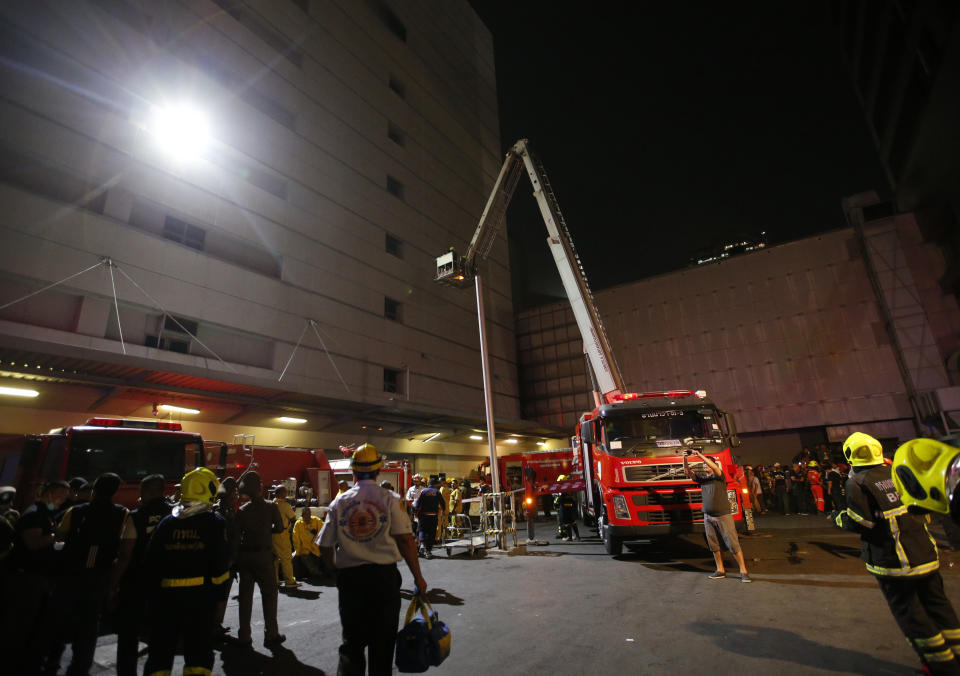 Firefighters work outside the scene of a fire at the Central World mall complex in Bangkok, Thailand, Wednesday, April 10, 2019. The fire had broken out in the Central World mall complex in Thailand's capital, with reports from emergency services saying it has caused a number of fatalities. (AP Photo/Sakchai Lalit)