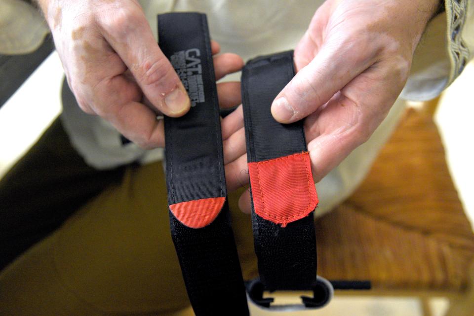David Halbout demonstrates the poor stitching of a fake tourniquet, right, at the Halbout home on Saturday, May 21, 2022 in Middletown, New Jersey. 
