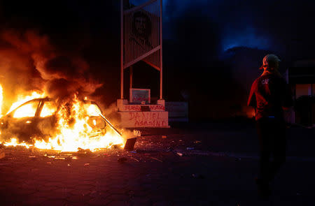 A demonstrator walks past a burning car during clashes with riot police during a protest against Nicaragua's President Daniel Ortega's government in Managua, Nicaragua May 30, 2018.REUTERS/Oswaldo Rivas