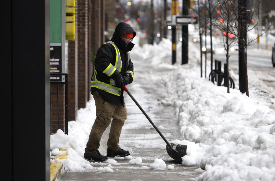 A worker shovels snow in Ottawa, as a winter storm warning is in effect, on Friday, Dec. 23, 2022. (Justin Tang /The Canadian Press via AP)