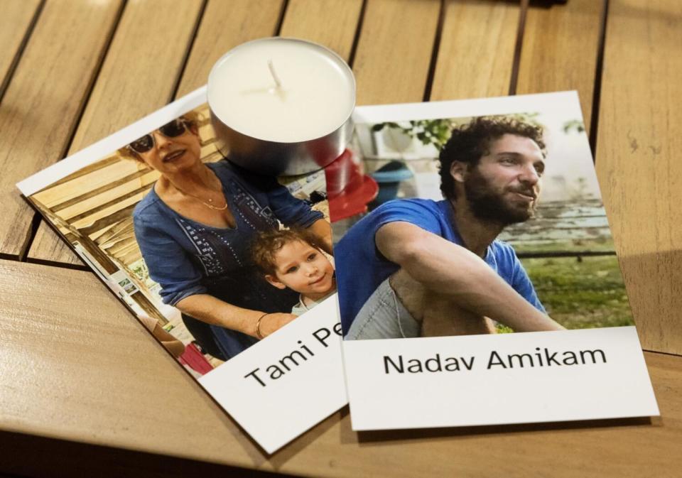 Pictures of a woman and child and a man with their names are displayed under a tea candle on a table.