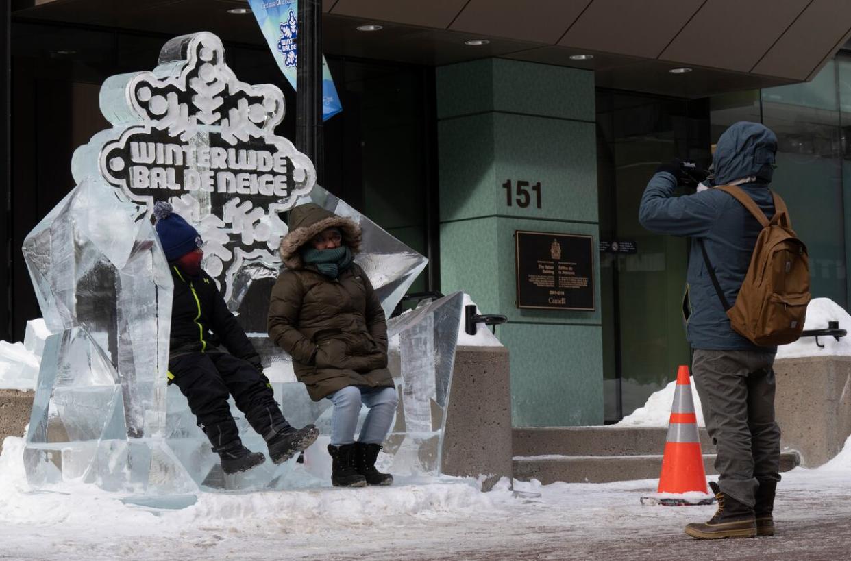 People take photos in front of an ice sculpture in downtown Ottawa on Feb. 3, 2023. The annual winter festival is set to return in February with some new attractions. (Adrian Wyld/The Canadian Press - image credit)