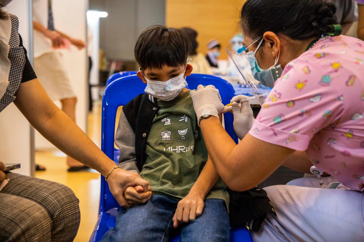 A teenage Thai boy holds his mother's hand while receiving his first dose of Pfizer's COVID-19 vaccine at Vachira Hospital on Sept. 21, 2021, in Bangkok, Thailand.