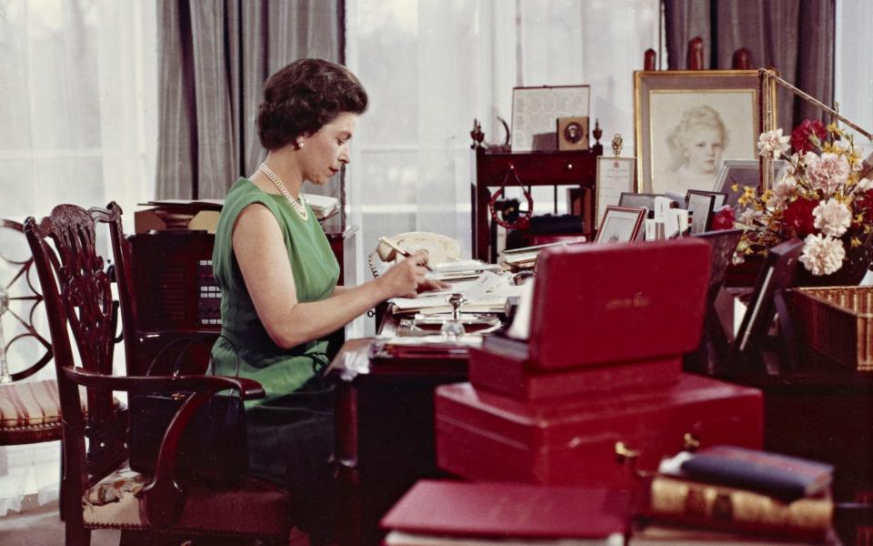 Queen Elizabeth at her desk in Buckingham Palace with a red despatch box in 1968 - THE ROYAL COLLECTION. Joan Williams