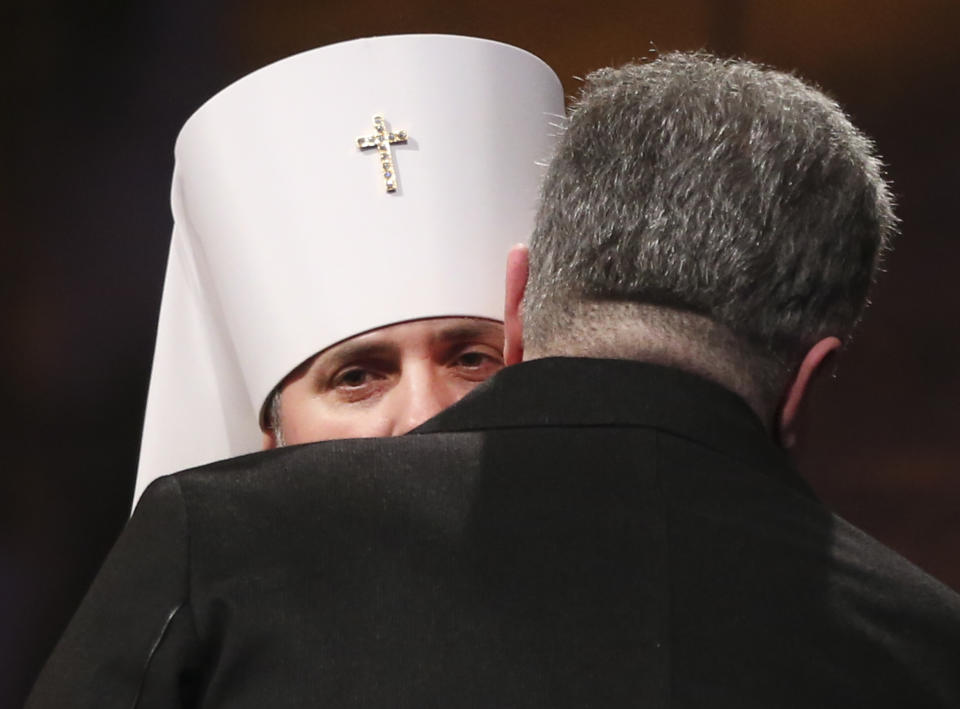 Ukrainian President Petro Poroshenko hugs newly elected head of independent Ukrainian church, Metropolitan of Kiev Epiphanius near the St. Sophia Cathedral in Kiev, Ukraine, Saturday, Dec. 15, 2018. Ukraine's Orthodox clerics gather for a meeting Saturday that is expected to form a new, independent Ukrainian church, and Ukrainian authorities have ramped up pressure on priests to support the move. (AP Photo/Efrem Lukatsky)