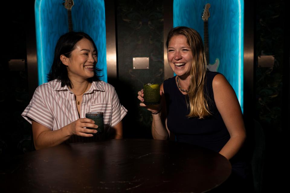 Inn Cahoots partners Michelle Chuang and Kristen Carson laugh with their cocktails in the Studio, a bar and gathering space adjacent to their hotel on East Sixth Street.