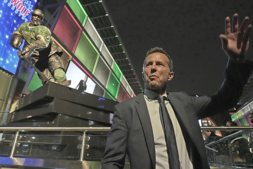 Former Dallas Stars player Mike Modano waves to fans in front of a statue of himself after an NHL hockey game between the Los Angeles Kings and the Stars in Dallas, Saturday, March 16, 2024. (AP Photo/LM Otero)