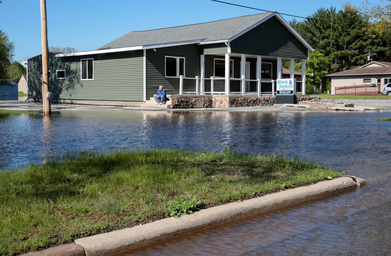 A man sits on a porch in a partially flooded neighborhood during the flooding along the Tittabawassee River, after two dam failures submerged parts of Midland, Michigan