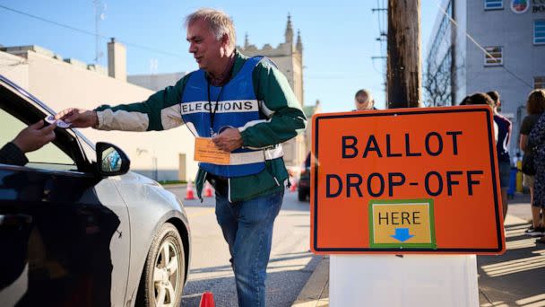 PHOTO: An official ballot collector for the Cuyahoga County Board of Elections gives a voter their 'I Voted' sticker after depositing their mail-in ballots into a collection box in Cleveland, Nov. 6, 2022, ahead of the midterm elections.  (Dustin Franz/AFP via Getty Images)