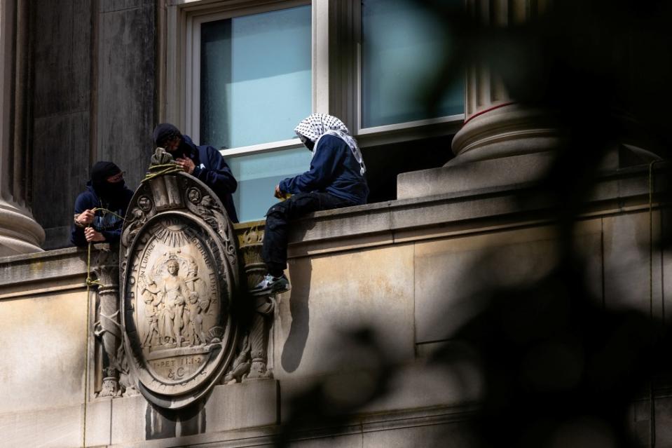 A pro-Palestinian protestor hangs out on a ledge at Hamilton Hall, the academic building taken over by student rioters. via REUTERS