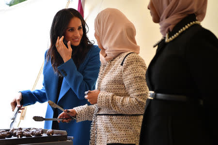 Meghan, Duchess of Sussex helps to prepare food at an event to mark the launch of a cookbook with recipes from a group of women affected by the Grenfell Tower fire at Kensington Palace in London, Britain September 20, 2018. Ben Stansall/Pool via Reuters