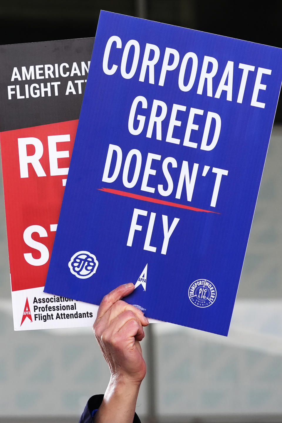 A flight attendant holds signs during flight attendant protest at O'Hare International Airport in Chicago, Tuesday, Feb. 13, 2024. They represent three different unions and work for several airlines including Southwest, American, and United. Each of the unions are in contract negotiations with the airlines and pushing for fair contracts. (AP Photo/Nam Y. Huh)