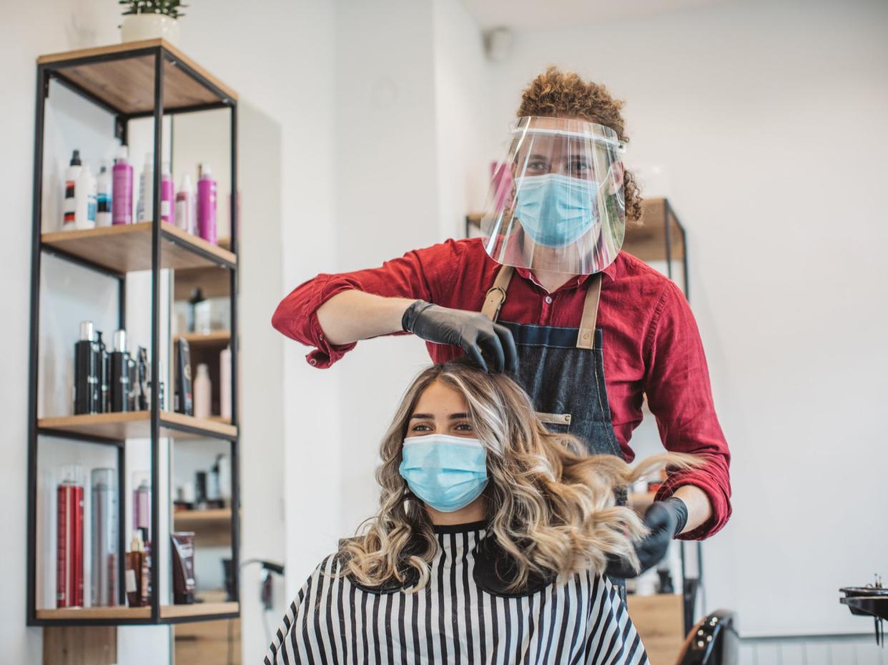 Young woman have hair cutting at hair stylist during pandemic isolation, they both wear protective equipment