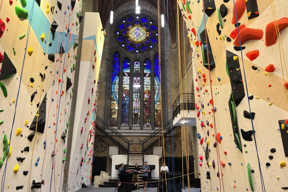 Varias personas se colocan detrás de las cuerdas de una pared de escalada en la reconvertida iglesia de San Antonio de Padua, ahora también conocida como el club de escalada Maniak Padoue, en Bruselas, Bélgica, el miércoles 21 de junio de 2023. En toda Europa, el continente que alimentó el cristianismo durante la mayor parte de dos milenios, muchas iglesias, conventos, monasterios y capillas permanecen vacíos debido a la disminución de creyentes y visitantes en el último medio siglo. Muchas están siendo reconvertidas para preservar su relevancia histórica y arquitectónica, mientras que otras se han abierto a actividades no religiosas para potenciar su uso, desde tiendas de ropa y paredes de escalada hasta clubes nocturnos. (AP Foto/Sylvain Plazy)