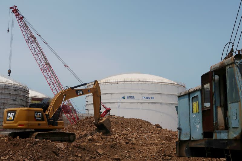 FILE PHOTO: A crude oil tank is seen behind a construction site at Hengli Petrochemical's new refining, petrochemical complex at Changxing island in Dalian