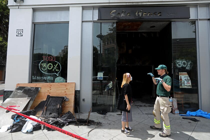 SANTA MONICA, CA - JUNE 01, 2020 - - Renato Akerman, right, with Community Emergency Response Team, talks with a former employee of Sake House which sustained major fire damage that was started by looters on Sunday night. The clean-up continued on Monday, June 1, 2020, when this photograph was taken. (Genaro Molina / Los Angeles Times)