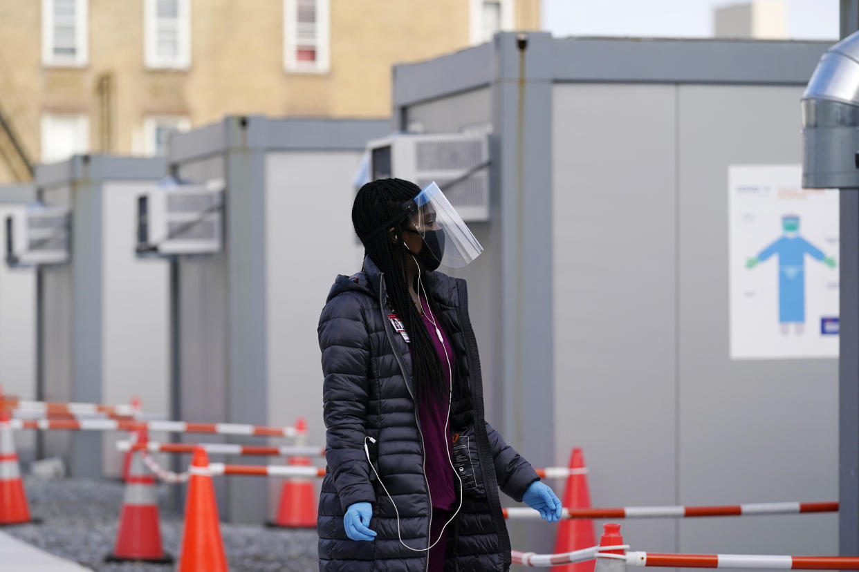 A worker wear a protective face shield walks between portable units set up for registration and testing at a New York City Health + Hospitals COVID-19 testing site in the Brooklyn borough of New York, Thursday, Nov. 19, 2020. (AP Photo/Kathy Willens)