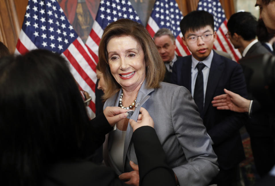 House Speaker Nancy Pelosi is given a lapel pin by a Hong Kong activist following a news conference on human rights in Hong Kong on Capitol Hill in Washington, Wednesday, Sept. 18, 2019. Behind Pelosi is Hong Kong activist Joshua Wong. (AP Photo/Pablo Martinez Monsivais)