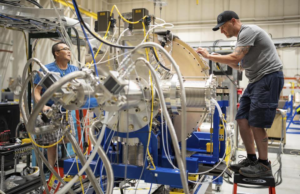 In this photo provided by Sandia National Laboratories, technicians work to test two of the cathode inductive voltage adder cells used in the Scorpius Injector being assembled at Sandia National Labs, June 8, 2023, in Albuquerque, N.M. Unable to physically validate the effectiveness and reliability of nuclear warheads since a 1992 underground test ban, the $1.8 billion Scorpius will allow experts to conduct subcritical experiments as early as 2027 in the atomic equivalent of a wind tunnel built for aircraft prohibited from flying. (Craig Fritz/Sandia National Laboratories via AP)