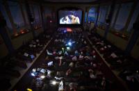 People use flashlights and wear newspapers on their heads while watching a late night screening of the movie "The Rocky Horror Picture Show". (Reuters)