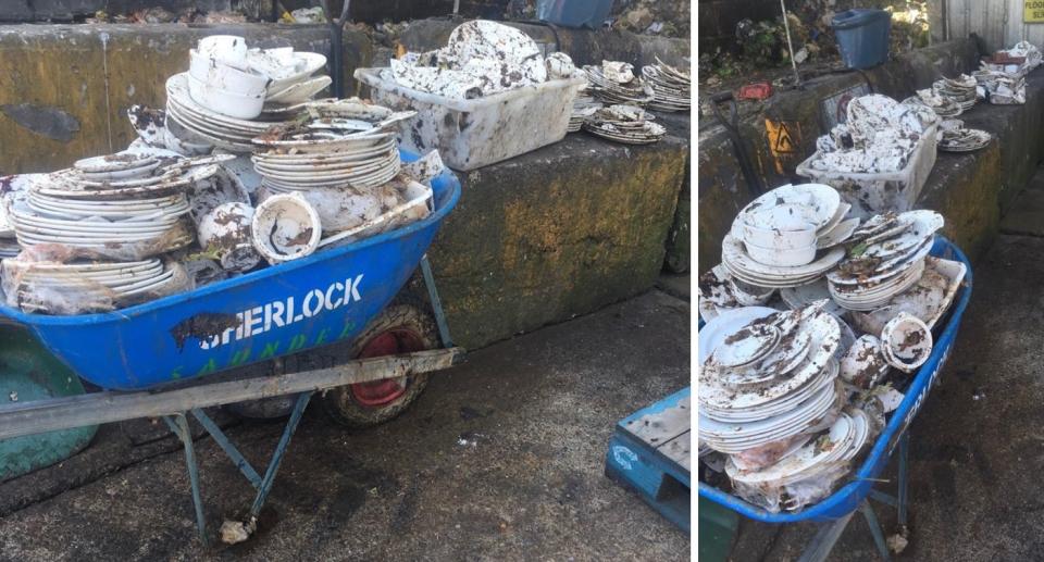 Piles of old crockery in wheelbarrow and on stone wall at recycling station