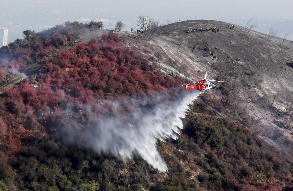 A helicopter drops water as a wildfire called the Getty fire burns on Kenter Canyon in Los Angeles, Monday, Oct. 28, 2019. (AP Photo/Ringo H.W. Chiu)