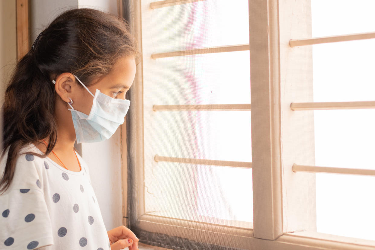 Sad young girl seeing through the window during home isolation watching out - Coronavirus or Covid-19 quarantine concept