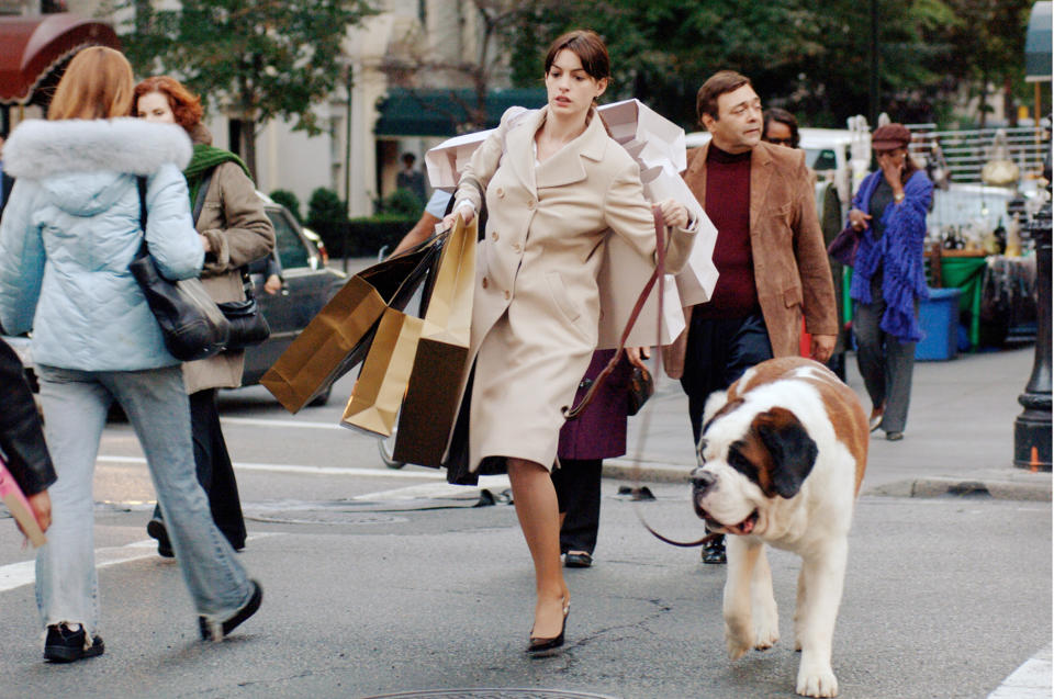 Anne Hathaway wearing heels while walking a dog and carrying a bunch of shopping bags in "The Devil Wears Prada"