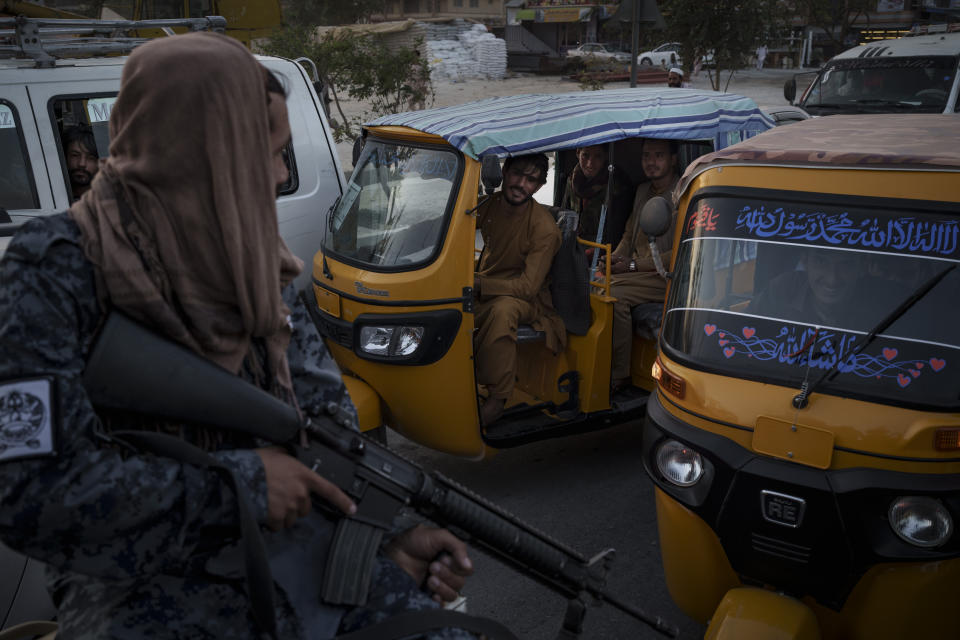 Afghan drivers and passengers stuck in a traffic jam look at Taliban fighters riding in the back of a vehicle in Kabul, Afghanistan, Monday, Sept. 20, 2021. (AP Photo/Felipe Dana)