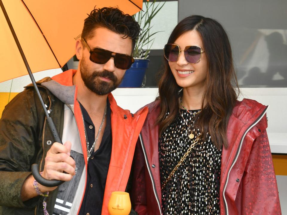 Dominic Cooper and Gemma Chan posing with drinks in their hands in August 2021.