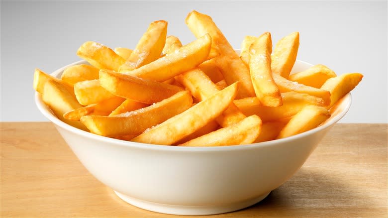 Cooked French fries in white bowl 