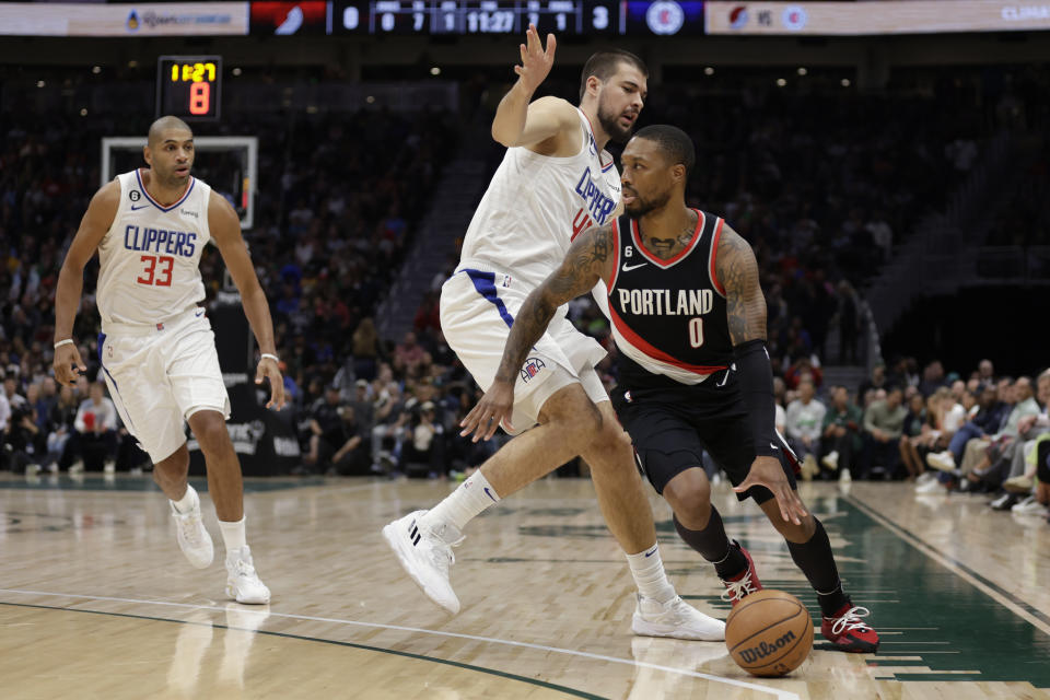 Portland Trailblazers' Damian Lillard drives around Los Angeles Clippers' Ivica Zubac with Nicolas Batum (33) behind during the first half of an NBA preseason basketball game, Monday, Oct. 3, 2022, in Seattle. (AP Photo/ John Froschauer)