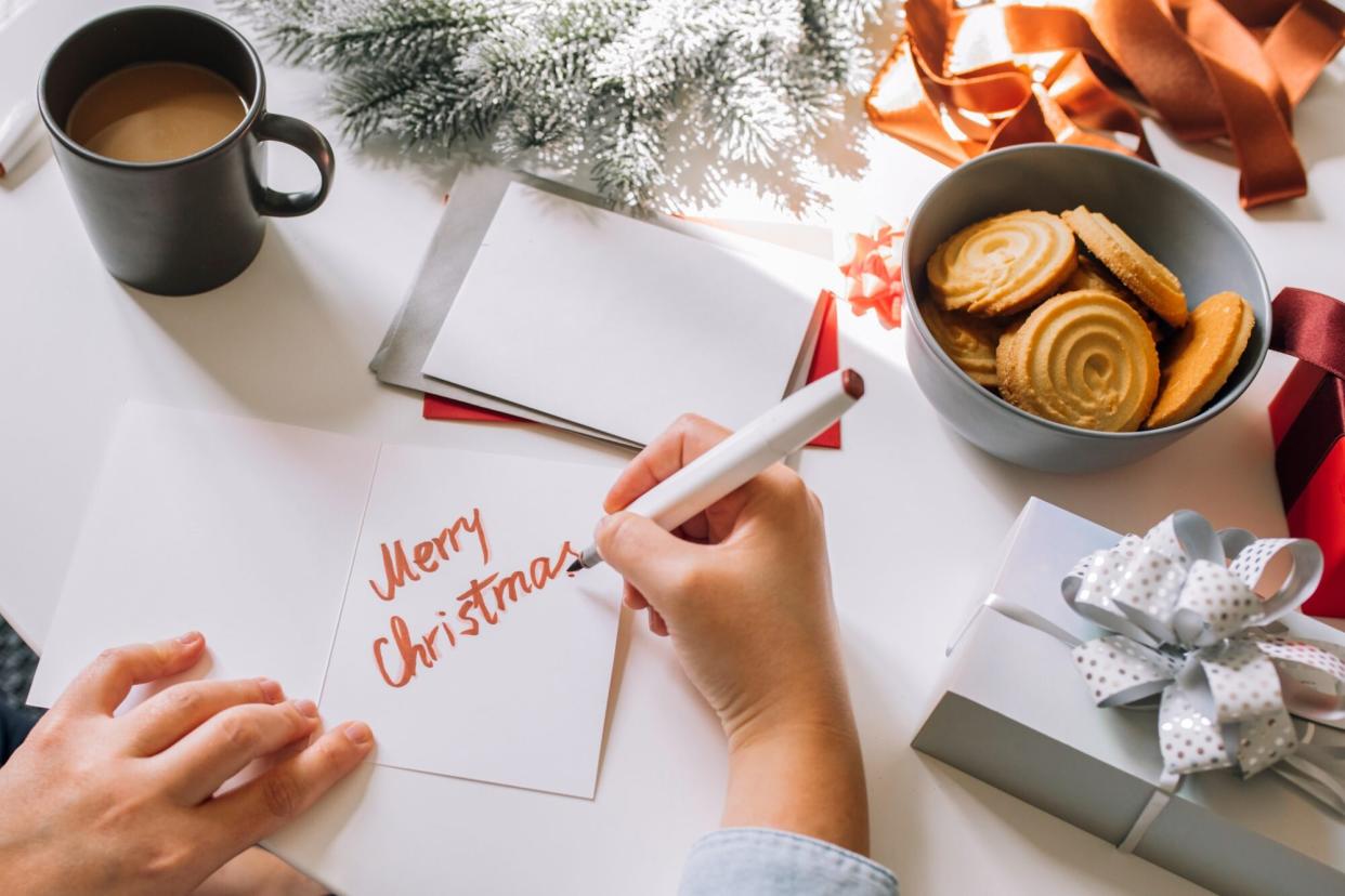 Happy woman writing Christmas cards at home, a close up.