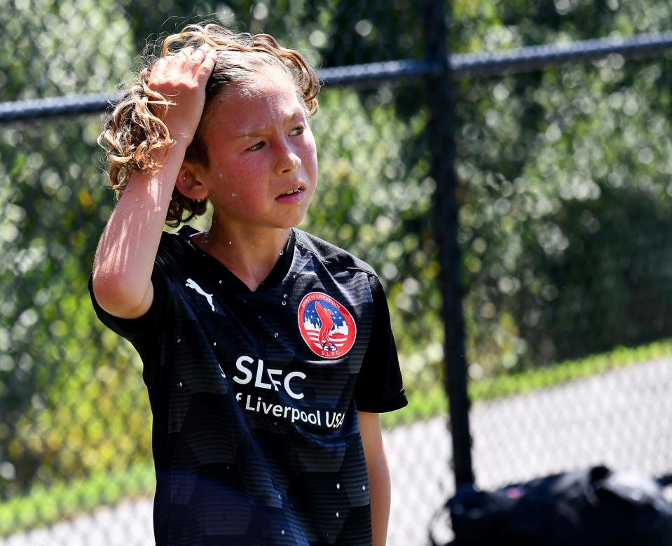 Wyatt McQuillan, 12, of Oxford wipes water away after pouring his bottle onto his head during a break from the Spirit of Liverpool soccer camp at the Pappas Recreation Complex in Auburn on Thursday. In response to the extreme heat, instructors scheduled frequent water breaks, provided shade canopies and quit early for the day.