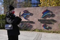 A visitor to the Shougang Park walks past the logos for the Beijing Winter Olympics and Paralympics in Beijing, China, Tuesday, Nov. 9, 2021. China on Monday, Dec. 6, 2021 threatened to take "firm countermeasures" if the U.S. proceeds with a diplomatic boycott of February's Beijing Winter Olympic Games. (AP Photo/Ng Han Guan)