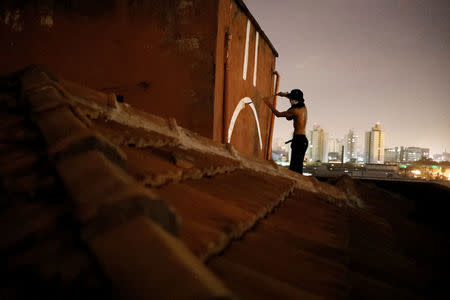 A "pichador", a graffiti artist who tags buildings and landmarks with angular, runic fonts, paints his personal signature, called "pichacao", on a wall on the roof of an apartment building, in Sao Paulo, Brazil, March 17, 2017. REUTERS/Nacho Doce