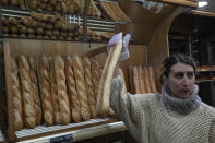 Mylene Poirier talks to a customer as she takes a baguette at a bakery, in Versailles, west of Paris, Tuesday, Nov. 29, 2022. The humble baguette -- the crunchy ambassador for French baking around the world -- is being added to the U.N.'s list of intangible cultural heritage as a cherished tradition to be preserved by humanity. UNESCO experts gathering Wednesday Nov. 30, 2022 in Morocco decided that the simple French flute deserved U.N. recognition. (AP Photo/Michel Euler)