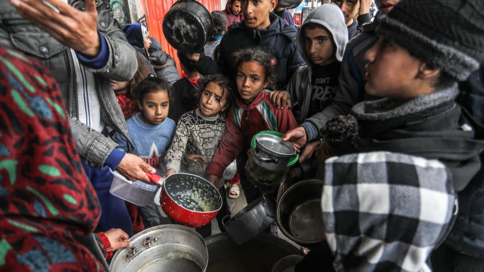 Palestinians holding empty bowls receive food distributed by volunteers amid a hunger crisis and famine risk due to the Israeli embargo imposed on the territory, in Rafah, the southern Gaza Strip on February 18. - Abed Rahim Khatib/Anadolu/Getty Images