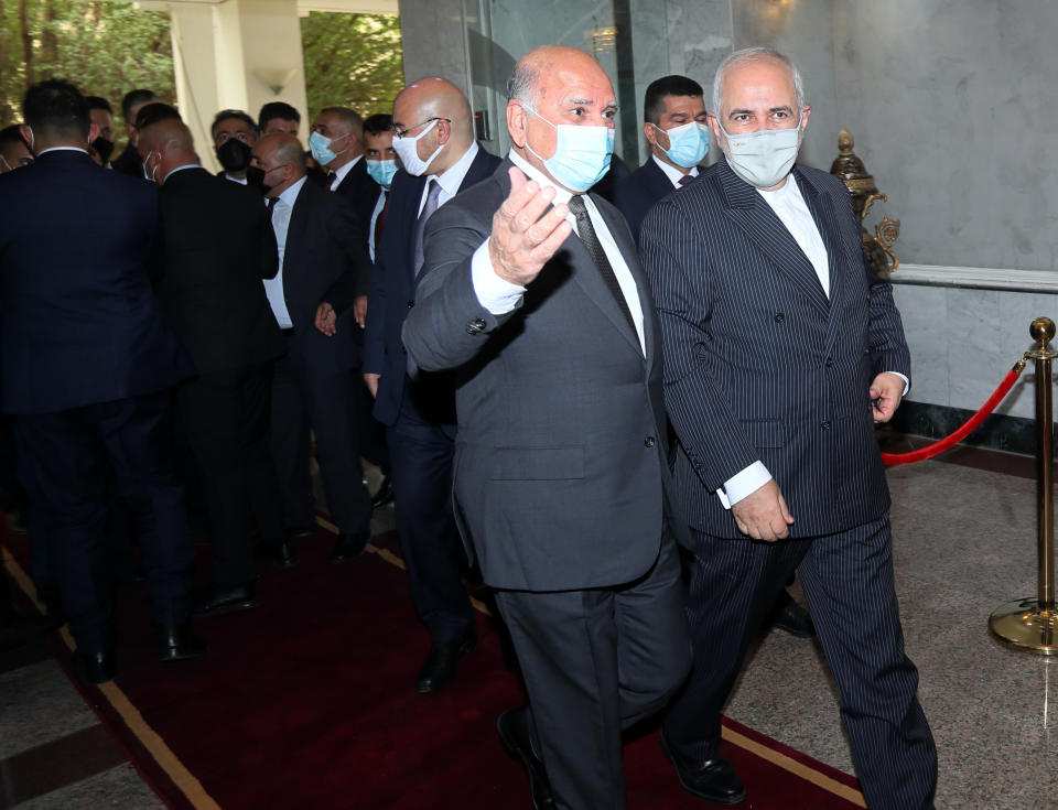 Iranian Foreign Minister Mohammad Javad Zarif, right, arrives to meet his Iraqi counterpart Fouad Hussein, center, in Baghdad, Iraq, Monday, April 26, 2021. (AP Photo/Khalid Mohammed)