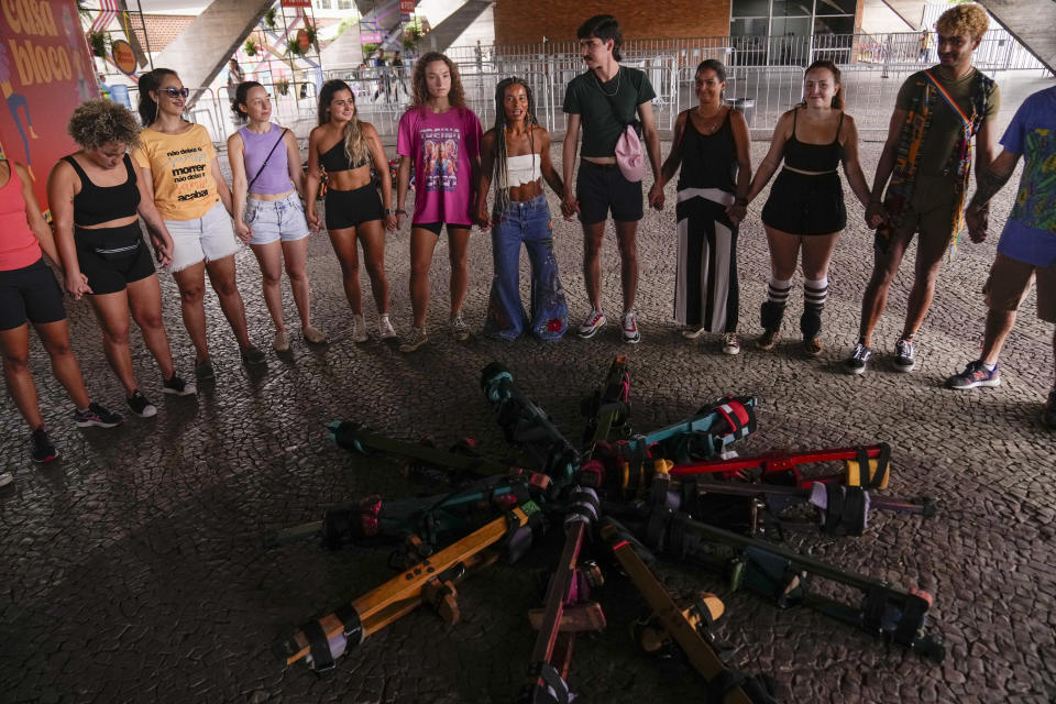 La instructora Raquel Potí, en el centro, imparte un taller de zancos ante el Museo de Arte Moderno en Río de Janeiro, Brasil, el sábado 27 de enero de 2024. Para Potí, subirse a los zancos es mucho más que un espectáculo: es ancestral y ritual, y un punto de partida para que la gente cambie de forma radical sus vidas y a sí mismos. (AP Foto/Silvia Izquierdo)