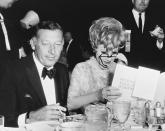 <p>Actress/comedian Lucille Ball uses her glasses to read the program as stand-up comedian Gary Morton enjoys a cigarette.</p>