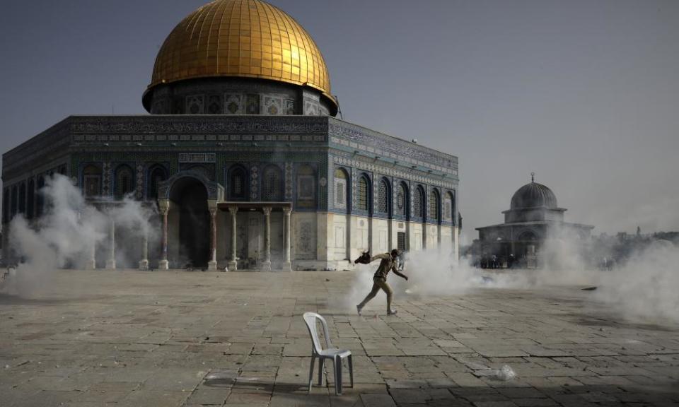 A Palestinian man runs away from teargas during clashes with Israeli security forces in front of the Dome of the Rock.